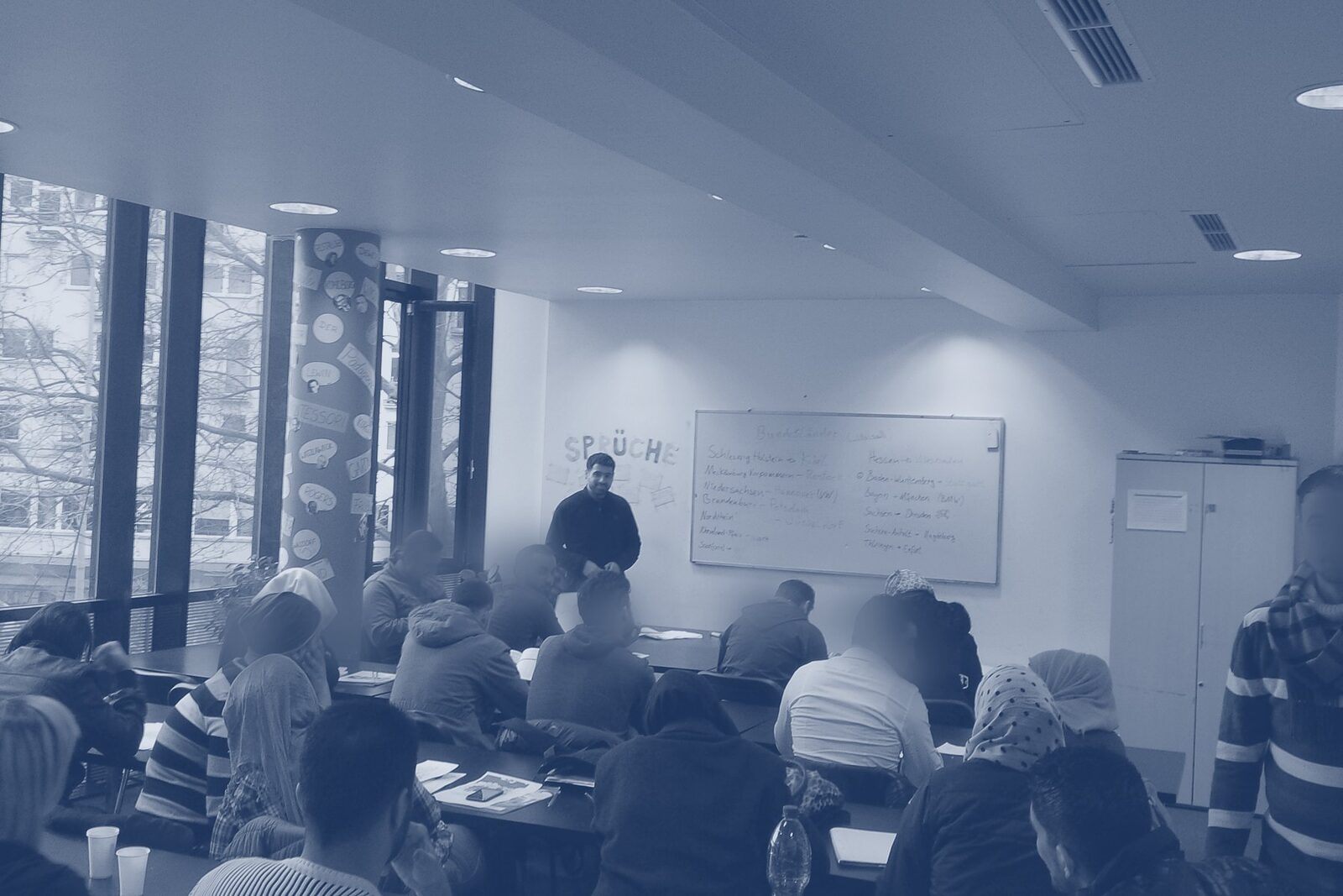 Kursraum mit Teilnehmenden, Trainer am Whiteboard